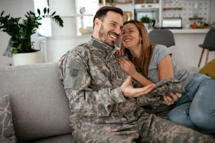 Happy soldier surprise his wife at home. Young soldier hugging wife.