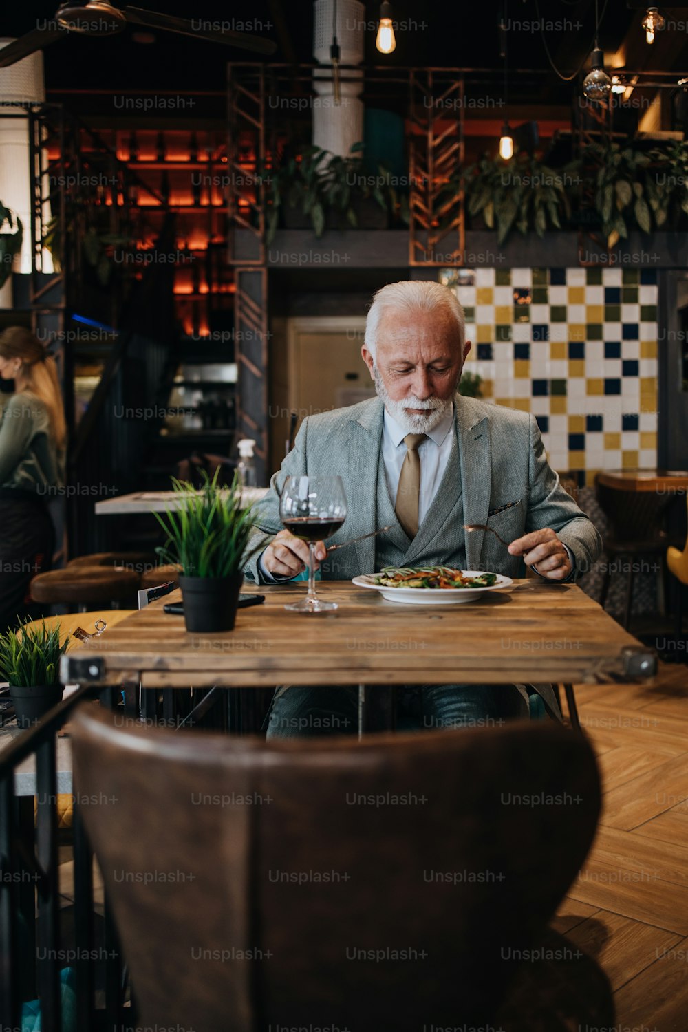 Glücklicher Geschäftsmann, der im Restaurant sitzt und zu Mittag isst. Er genießt köstliches Essen und Wein.