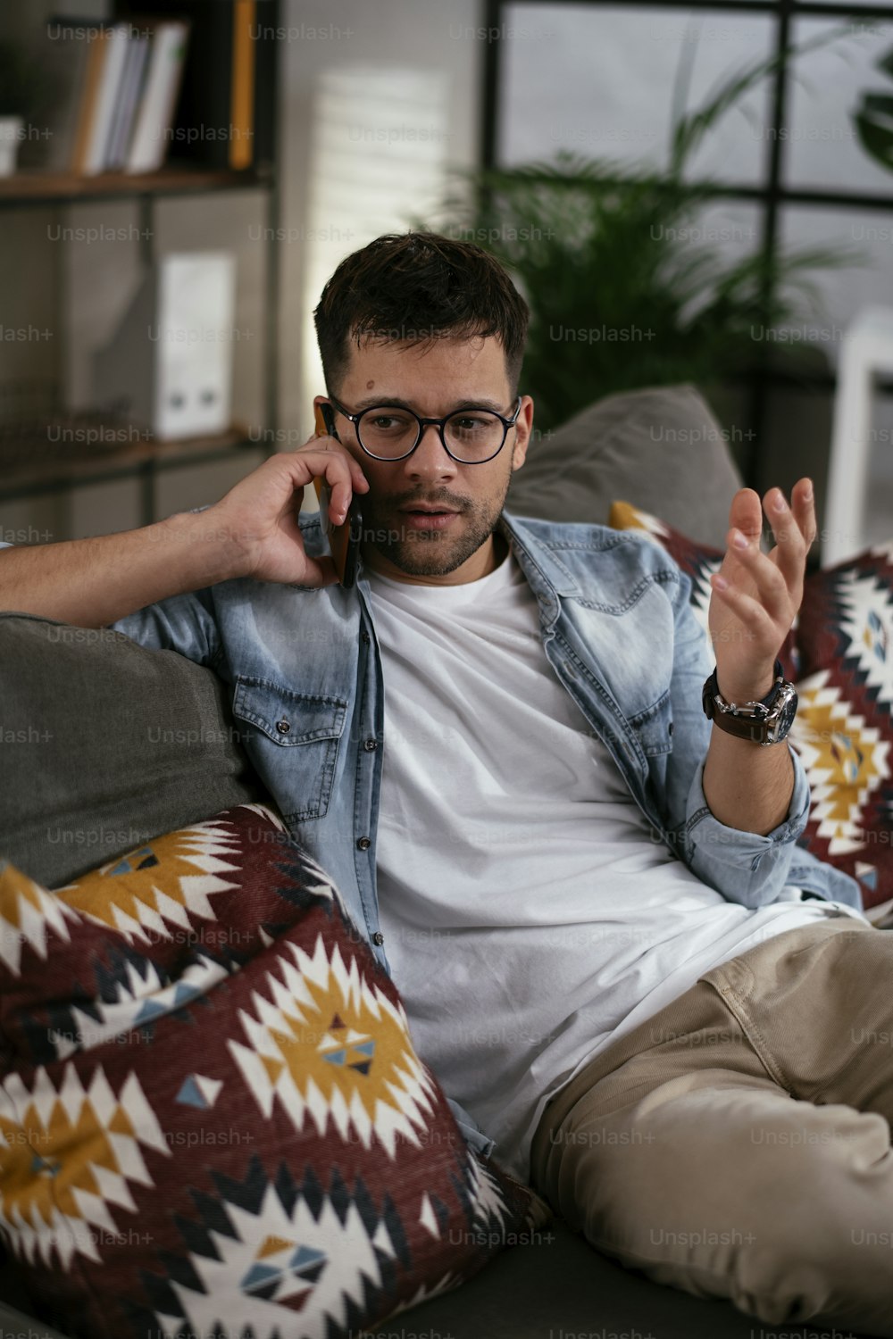 Young man talking on the phone while sitting on sofa. Happy man using the phone.