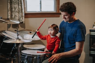 Père apprenant à son petit garçon à jouer de la batterie. Parent avec enfant en bas âge qui s’amuse et passe du temps ensemble. Papa et enfant jouant de la musique. Activité de loisir et de loisirs en famille.