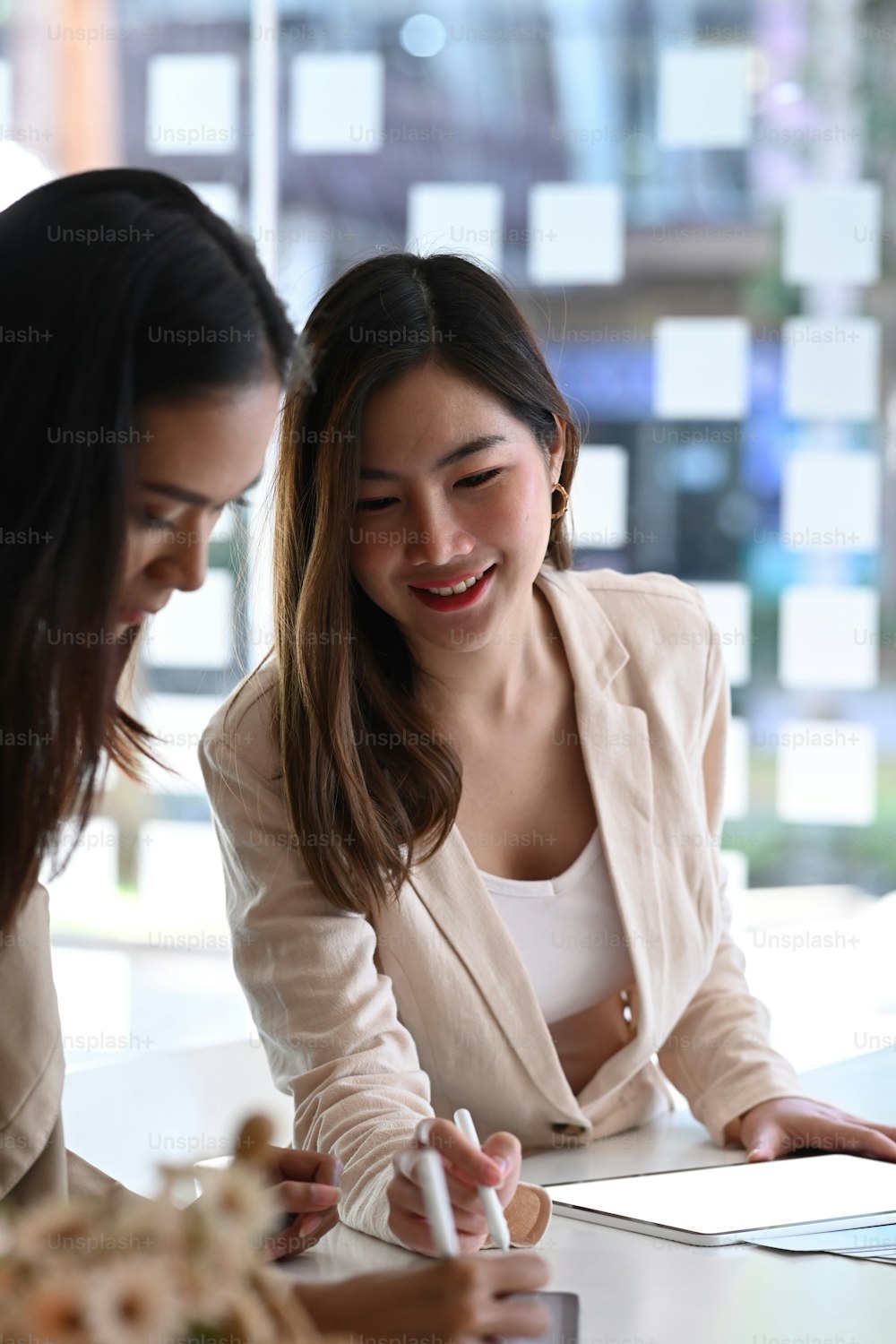 Portrait de deux femmes d’affaires ayant une réunion informelle dans un bureau moderne.