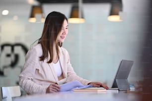 Una ejecutiva haciendo papeleo en el lugar de trabajo y usando una tableta de computadora para el análisis de datos.