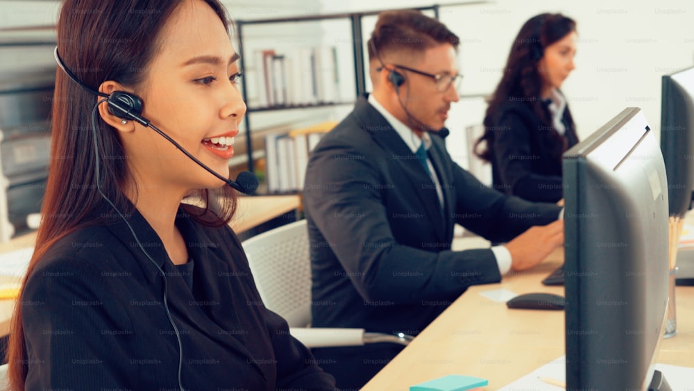 Business people wearing headset working in office to support remote customer or colleague. Call center, telemarketing, customer support agent provide service on telephone video conference call.