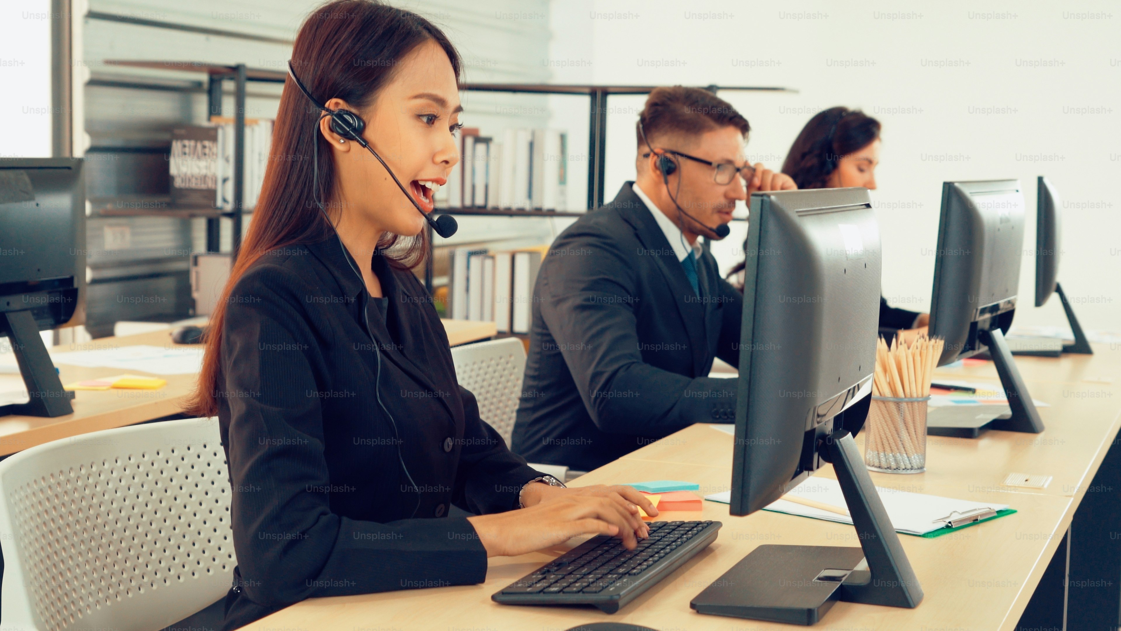 Business people wearing headset working in office to support remote customer or colleague. Call center, telemarketing, customer support agent provide service on telephone video conference call.