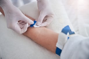 Ritratto ravvicinato delle mani dell'infermiera in guanti che ricevono il trattamento gocciolamento vitaminico per il paziente nel centro estetico