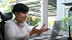 A young man freelancer using computer laptop video call communicate with business colleague at home.