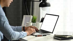 Vue latérale d’un homme d’affaires travaillant sur un ordinateur portable avec un écran vide dans son espace de travail.