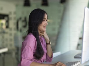 Vista laterale della donna d'affari che lavora con il computer sul tavolo da lavoro nella moderna stanza dell'ufficio