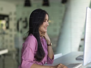 Side view of businesswoman working with computer on worktable in modern office room