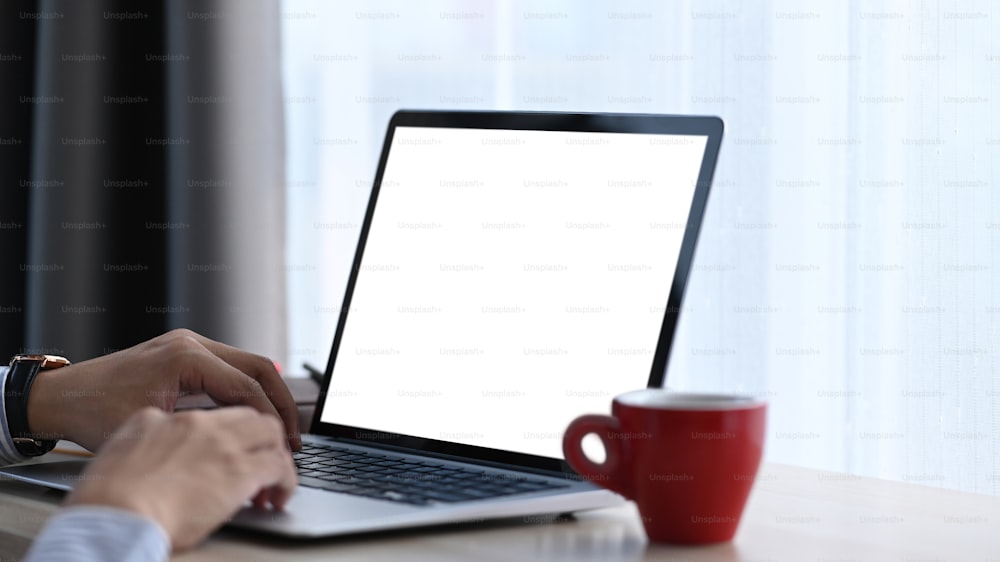 職場でノートパソコンで作業する男性の手の接写。アドバタイズテキスト用の空の画面。