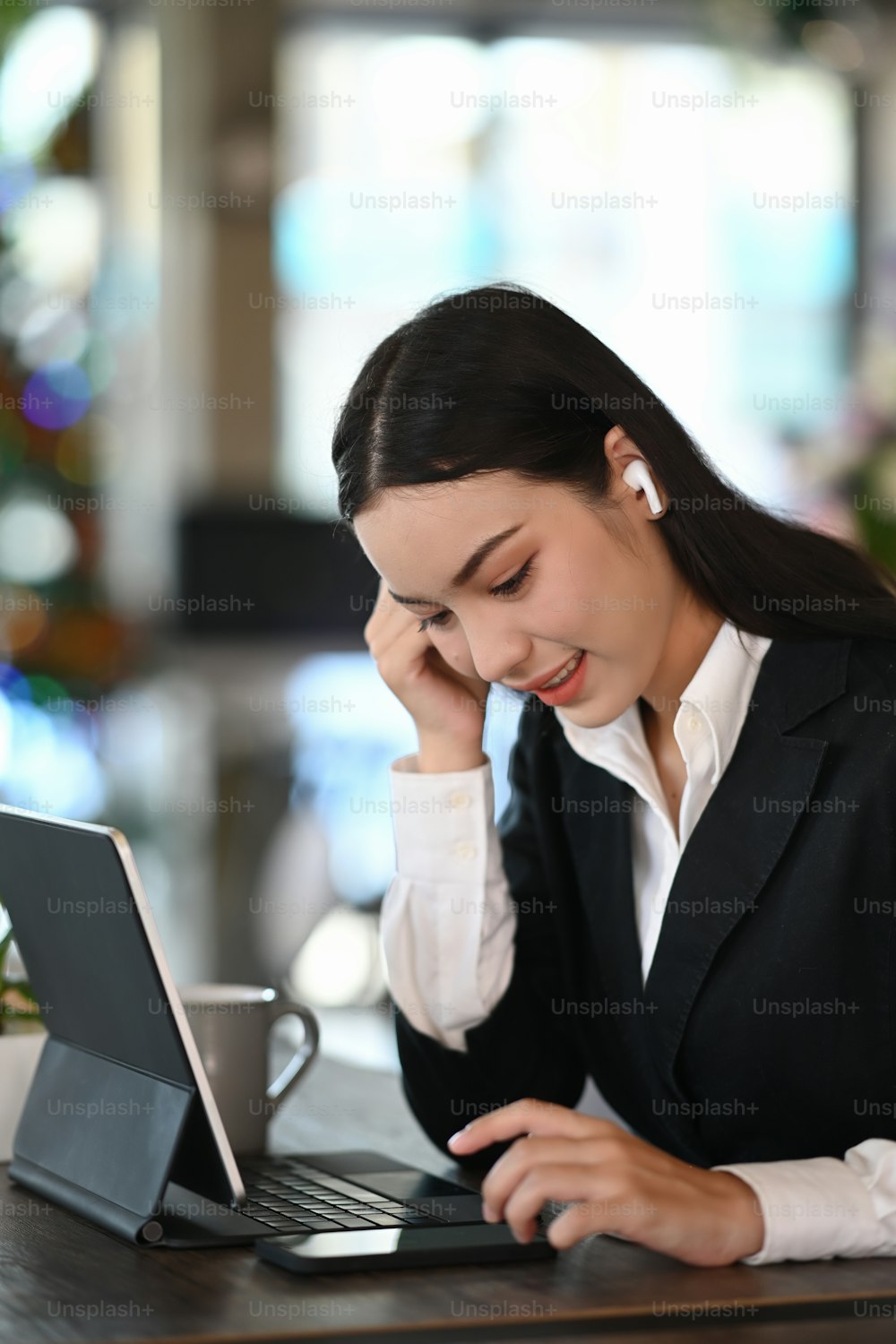 Portrait of young businesswoman with earphone working on computer talet at her workplace.