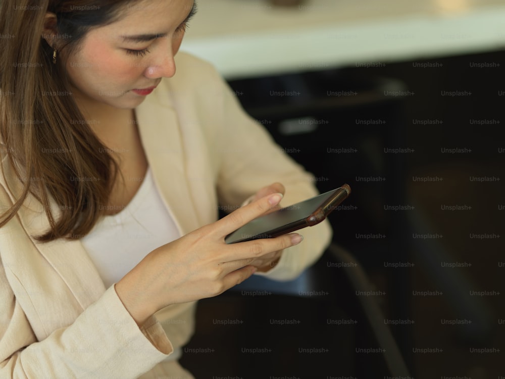 Retrato de mujer de negocios usando un teléfono inteligente mientras está sentada en la cafetería