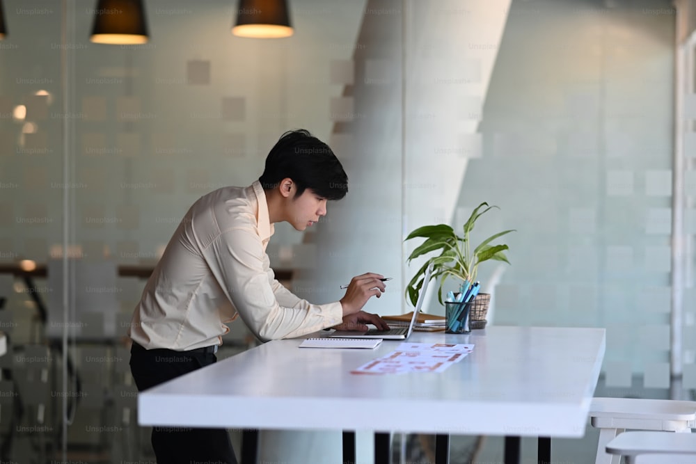 A male designer working on browsing information for project on computer laptop at office.