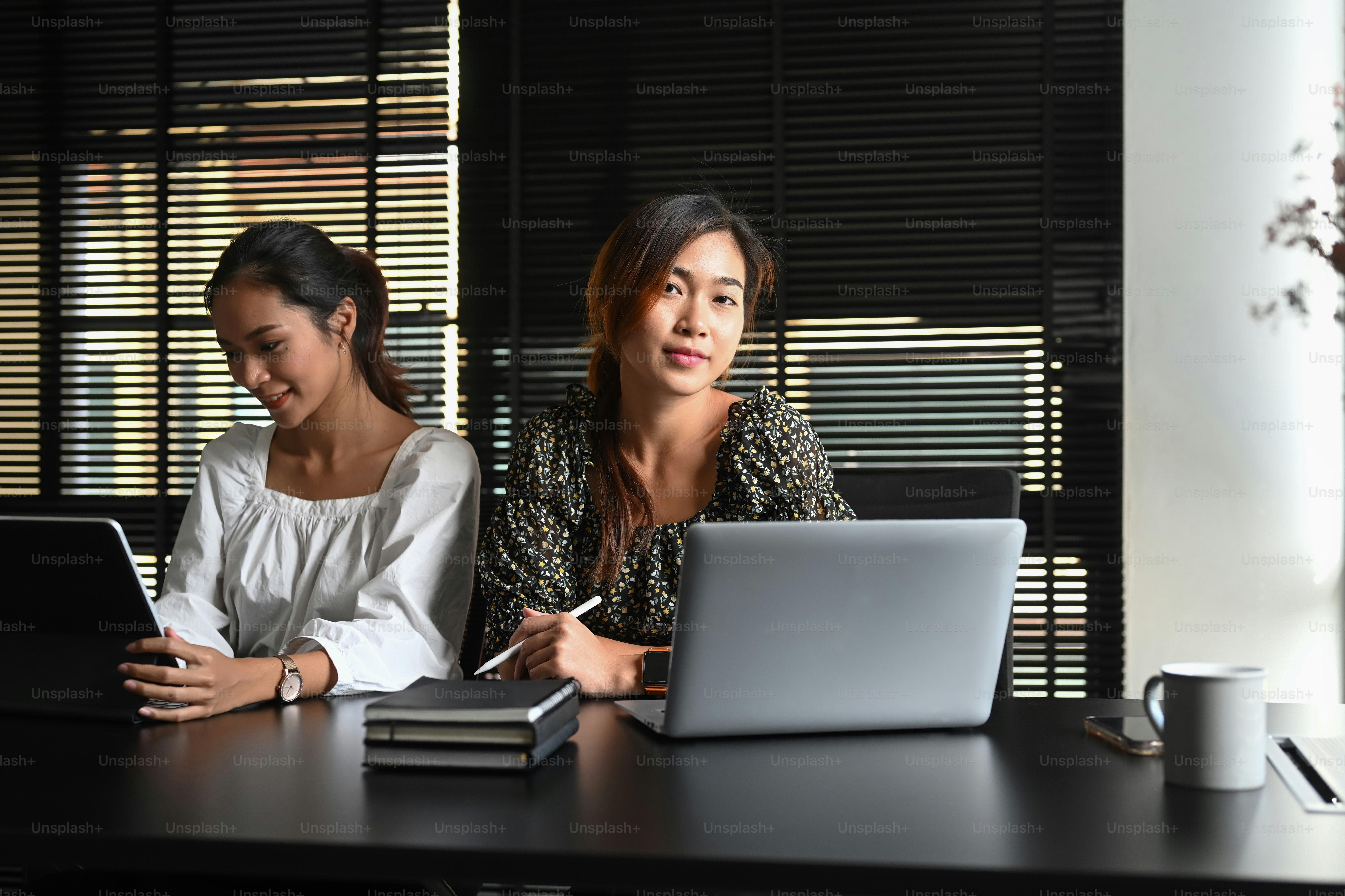 Image of two Asian woman discussing business matters in office.