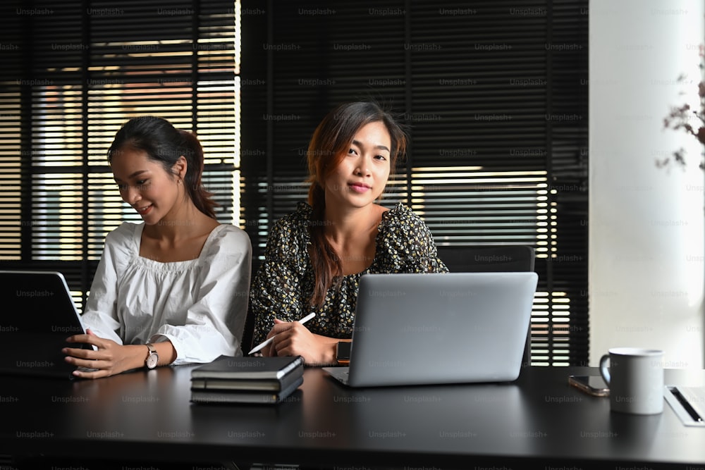 オフィスでビジネス問題を議論する2人のアジア人女性の画像。