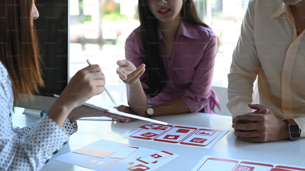 Group of creative designer planning application process development prototype for application on smartphone at meeting table.