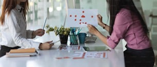 Side view of two businesswoman consulting on their project with paperwork in meeting room