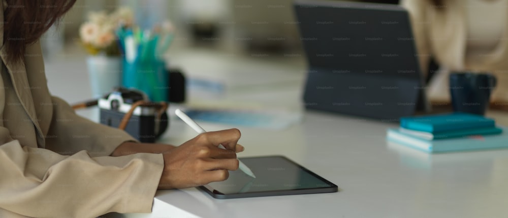 Side view of businesswoman hand working with digital tablet with stylus pen on worktable