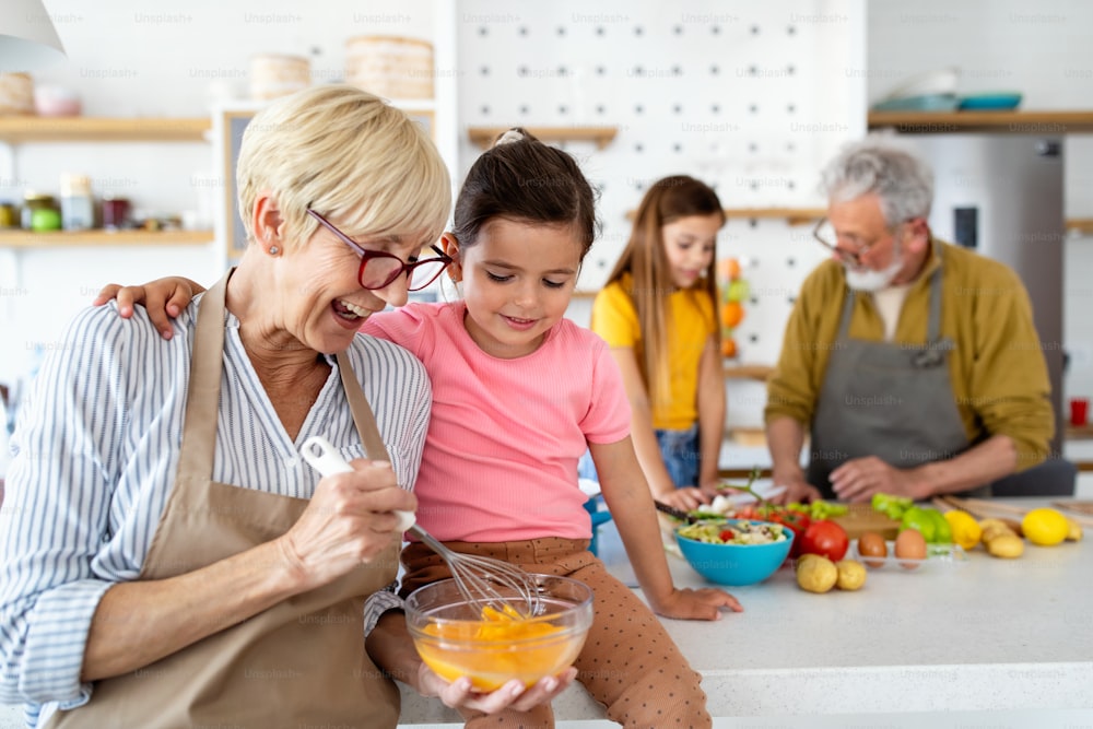 Familia alegre que pasa un buen rato juntos mientras cocina en la cocina. Concepto de abuelos, nietos.