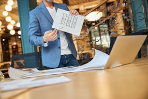 Cropped photo of man in blazer pointing to a schematic picture while having a video-call