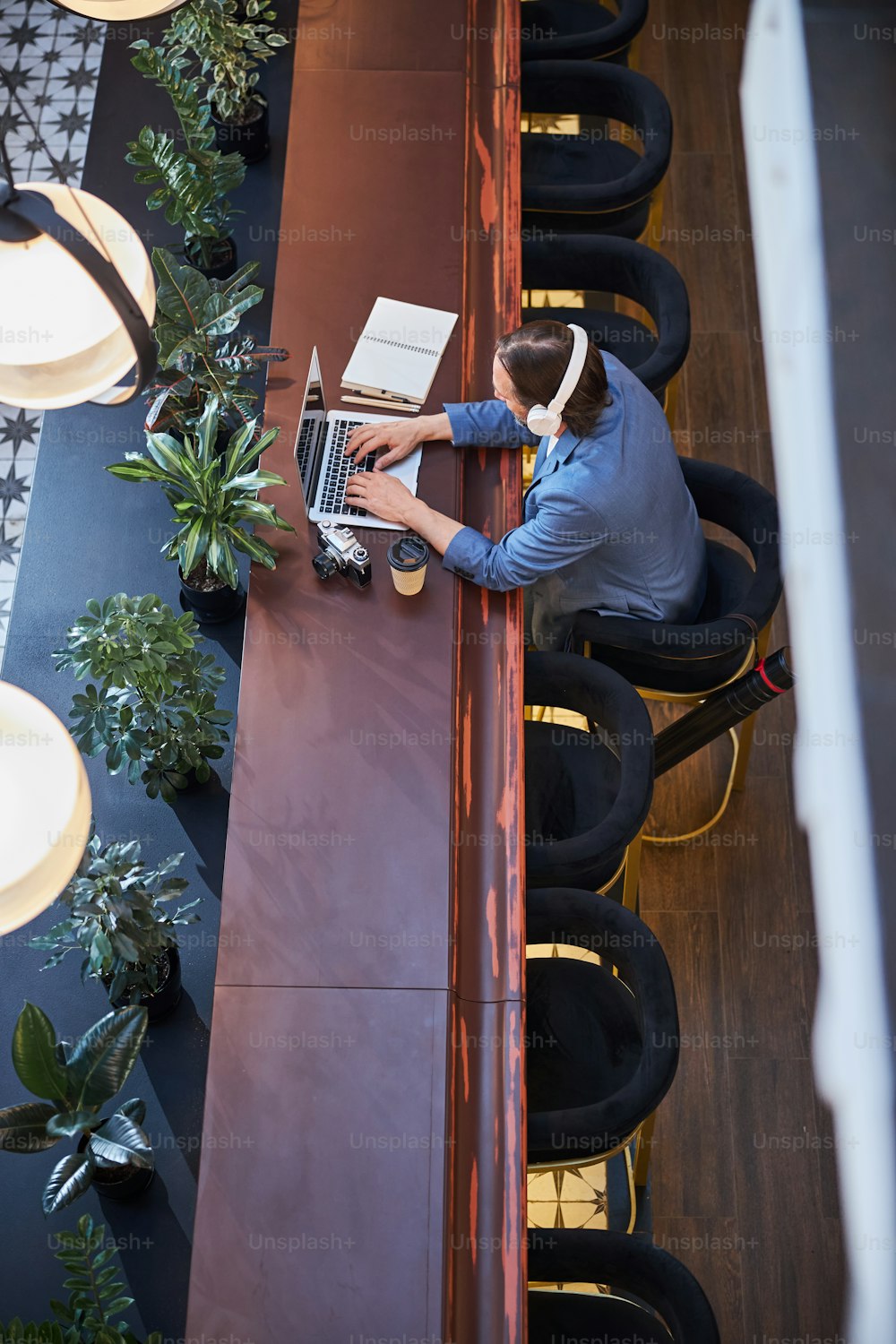 Homem concentrado em fones de ouvido puxando seu laptop enquanto fazia algum trabalho remoto de seu hotel aconchegante