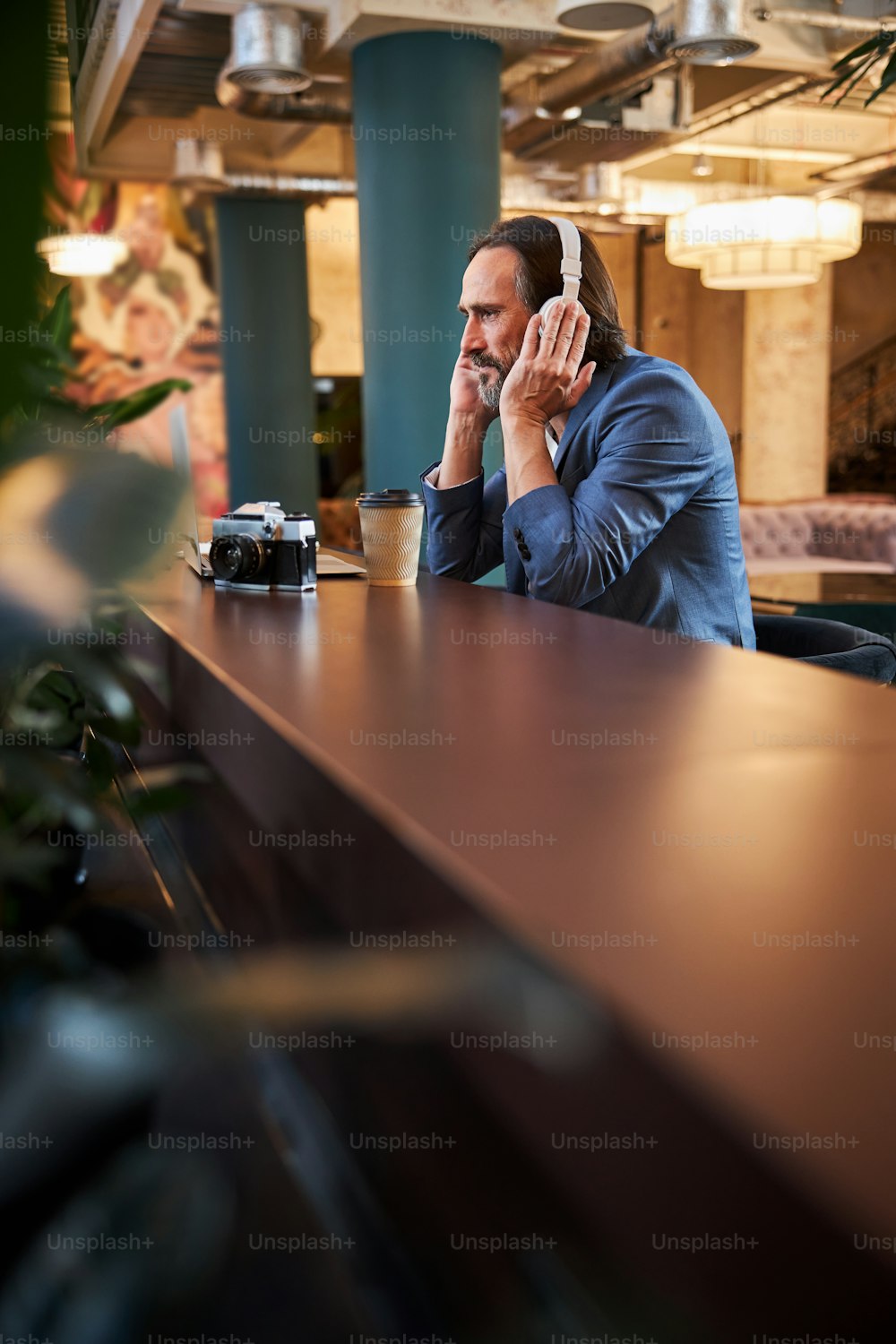 Focused brunette man pressing his hands to his headphones while taking in the music