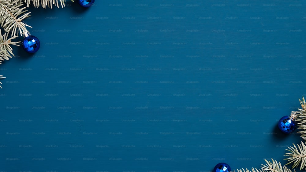 松の木の枝で作られたクリスマスフレームは、青い背景にボールを飾りました。ミニマルなスタイル。メリークリスマスと新年あけましておめでとうございますグリーティングカードのデザイン