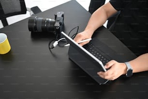 男性写真家がクリエイティブなワークスペースでパソコンのタブレットで写真をレタッチしている様子を撮影した写真。