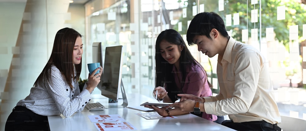 Cliché d’un groupe de jeunes développeurs et concepteurs d’interface utilisateur asiatiques est une application de développement pour téléphone mobile dans une salle de réunion.