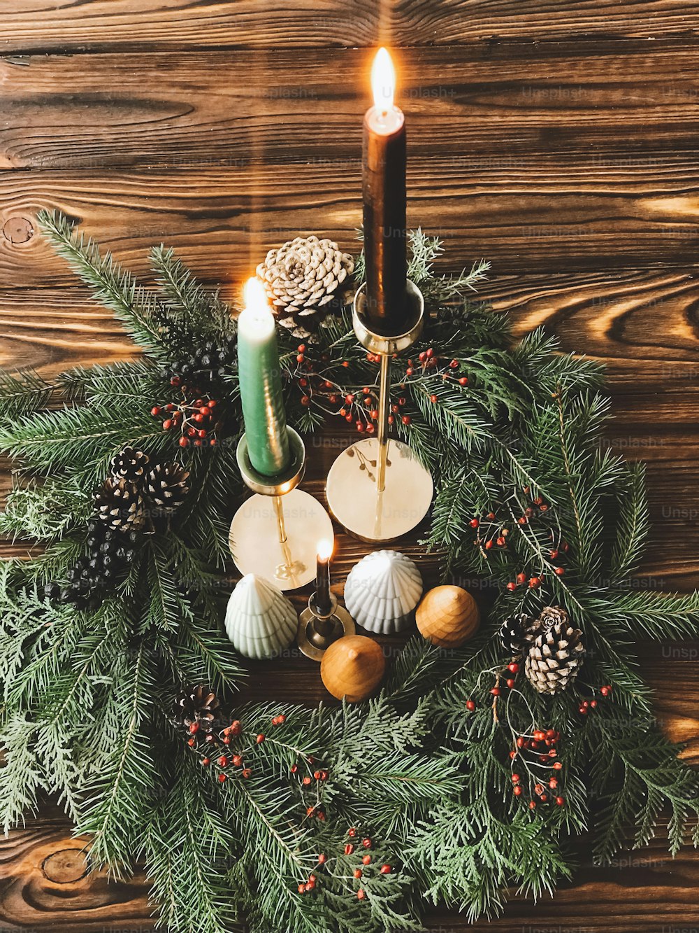 Christmas wreath with candles, pine cones, trees and fir branches on rustic wood, christmas table setting and decor. Festive simple natural home decorations. Happy holidays and Merry Christmas!