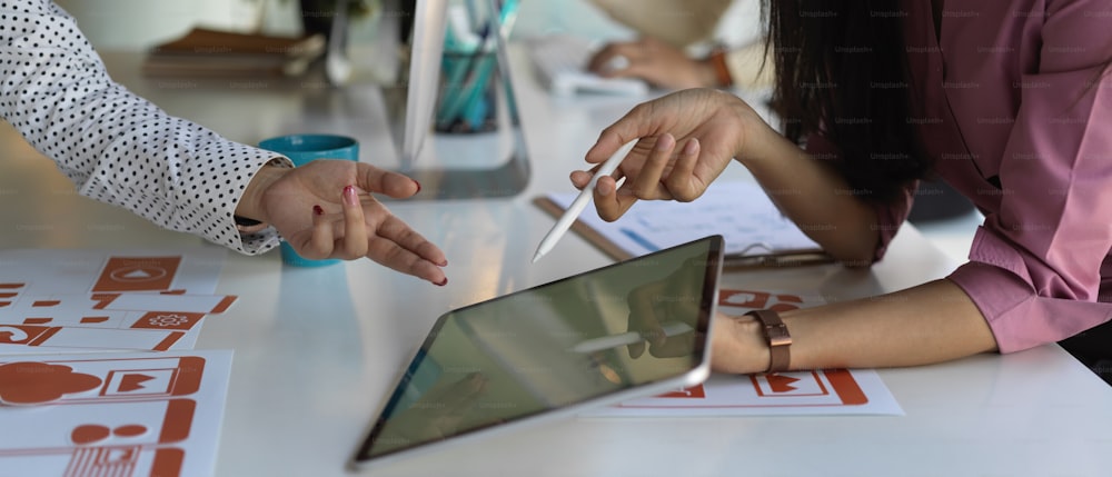 Vista laterale della riunione del team di sviluppatori dell'interfaccia utente sul loro progetto con tablet e documenti