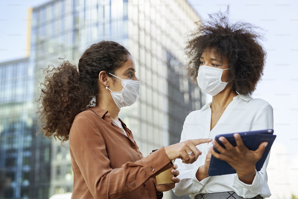 Two businesswomen with face masks in the city