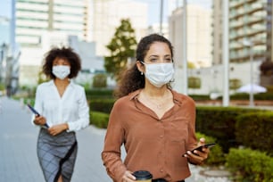 Empresárias caminhando pela cidade com máscaras faciais de proteção