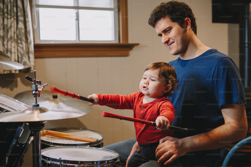 Père apprenant à son petit gar�çon à jouer de la batterie. Parent avec enfant en bas âge qui s’amuse et passe du temps ensemble. Papa et enfant jouant de la musique. Activité de loisir et de loisirs en famille.