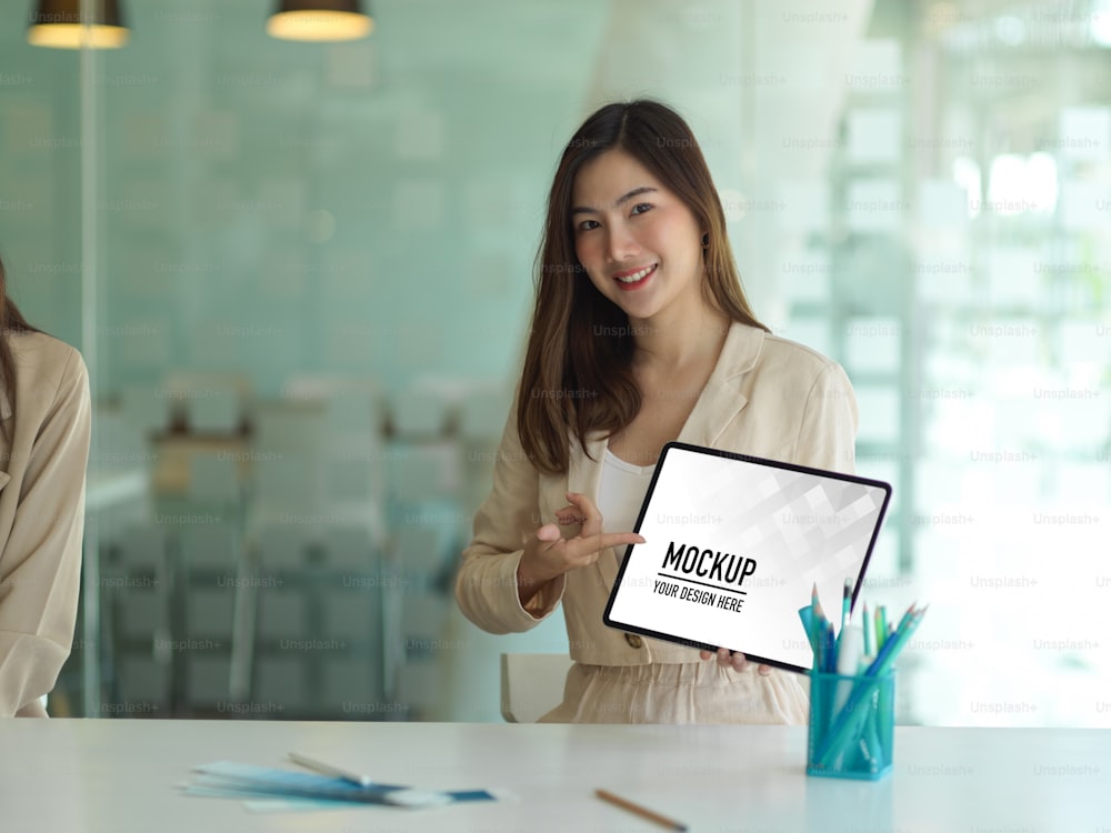 Portrait of businesswoman presenting her project on mock up tablet in meeting room