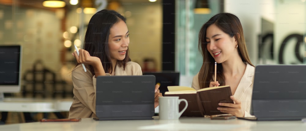 Ritratti di due donne d'affari che si consultano sul loro progetto con tablet nella sala riunioni
