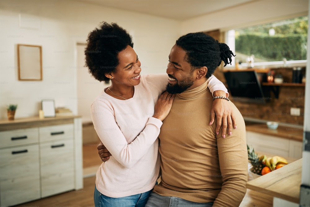 집에서 이야기하는 동안 포옹하는 행복한 흑인 커플.
