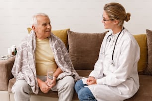 Médico da mulher nova dar uma consulta ao homem idoso durante a visita domiciliar