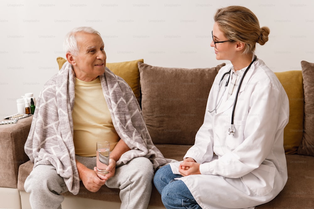 Une jeune femme médecin donne une consultation à un homme âgé lors d’une visite à domicile