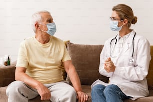Doctora joven da una consulta a un anciano durante una visita domiciliaria