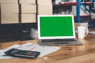 Computer with green screen display in warehouse storage room . Delivery and transportation software concept .