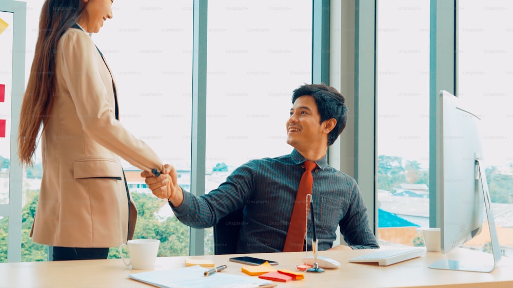 Two business people talk project strategy at office meeting room. Businessman discuss project planning with colleague at modern workplace while having conversation and advice on financial data report.