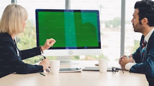 Pessoas de negócios na sala de conferências com tela verde chroma key TV ou computador na mesa do escritório. Grupo diversificado de empresário e empresária em reunião em videoconferência.