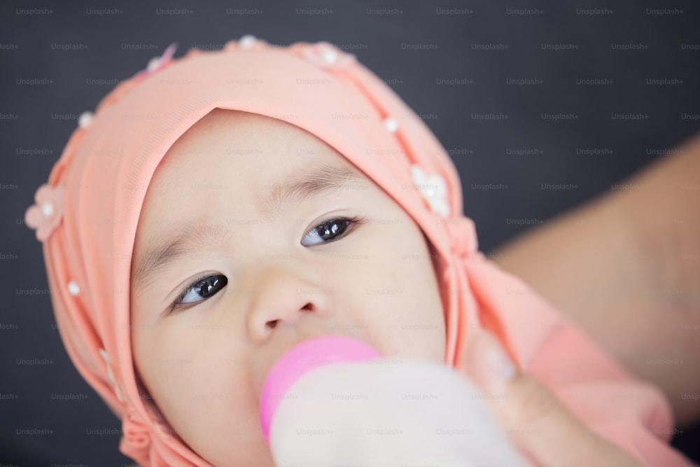 赤ん坊に哺乳瓶で授乳するイスラム教徒の母親