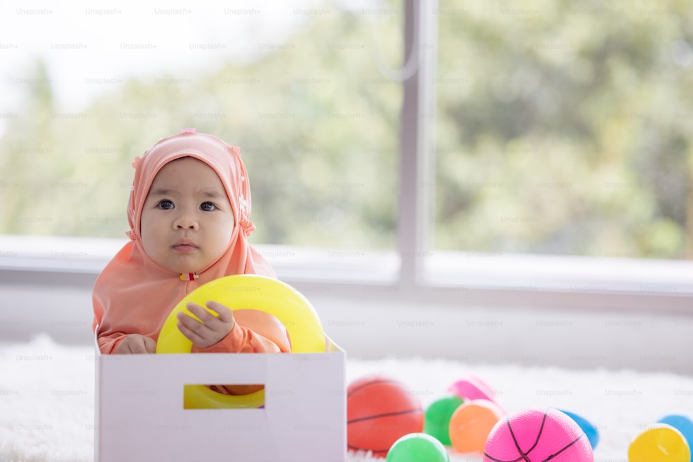 Muslim Baby spielt mit buntem Spielzeug im Wohnzimmer