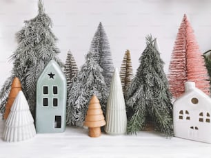 Weihnachtsszene, Bäume und Häuser auf weißem rustikalem Hintergrund.  Frohe Feiertage und frohe Weihnachten! Miniatur-Weihnachtsbäume und verschiedene Häuser.