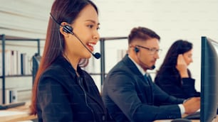 Personas de negocios que usan auriculares que trabajan en la oficina para apoyar a clientes o colegas remotos. El centro de llamadas, el telemarketing y el agente de atención al cliente brindan servicio en llamadas telefónicas de videoconferencia.