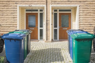 Cassoni della spazzatura fuori dalle porte d'ingresso, etichettati per il riciclaggio, i rifiuti da giardino e i rifiuti del Grahame Park Estate di Londra