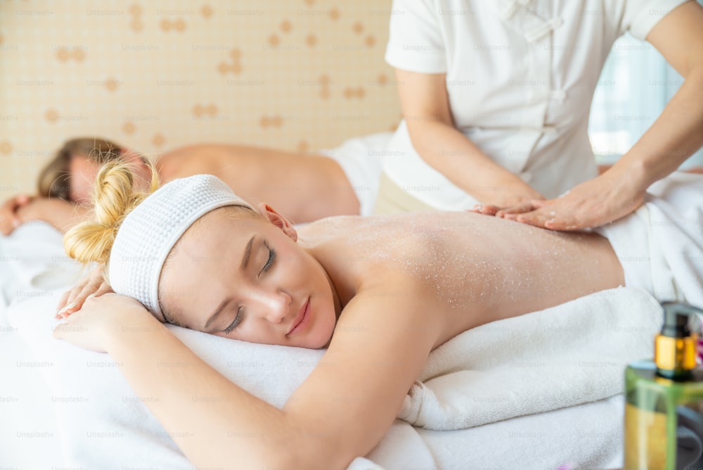 Caucasian woman lying on spa bed get back massage scrub with spa salt at beauty salon