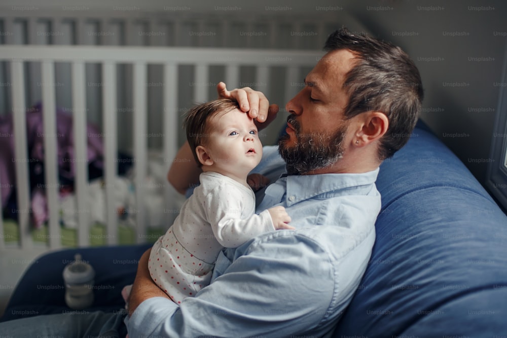 Fathers Day. Caucasian father talking to newborn baby girl. Parent holding rocking child daughter in hands. Authentic lifestyle happy parenting fatherhood moment. Single dad family home life.